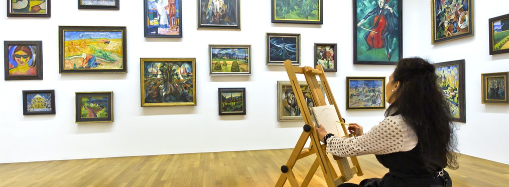 Eine Frau sitzt in einem Ausstellungssaal des Kunstmuseums Bonn an einer Staffelei und malt