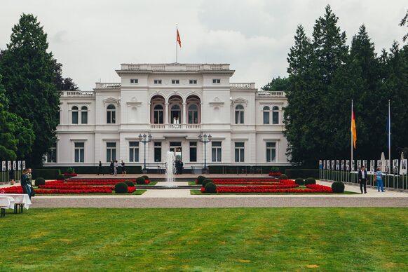 Außenansicht der Villa Hammerschmidt mit Springbrunnen und Blumenbeeten im Park