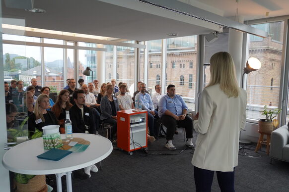 Seminar in einem Raum mit Fensterfront im Hintergrund.