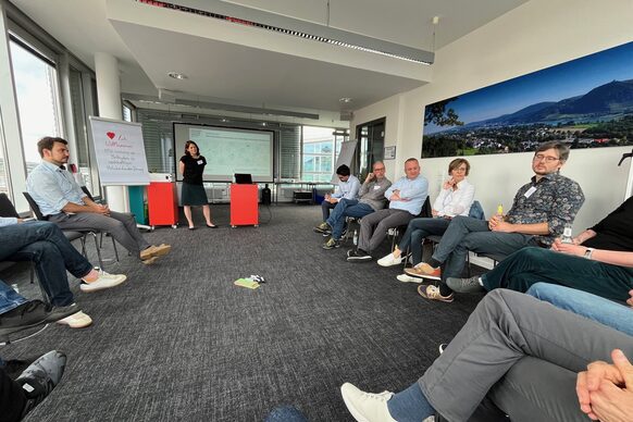 Personen sitzen bei einem Seminar im Kreis und diskutieren