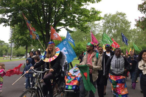 Mehrere Personen mit Fahnen der SDG gehen zu Fuß oder fahren mit dem Rad