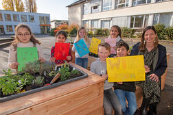 Schulkinder und Lehrerin mit Danke-Schildern an der Grünen Insel.