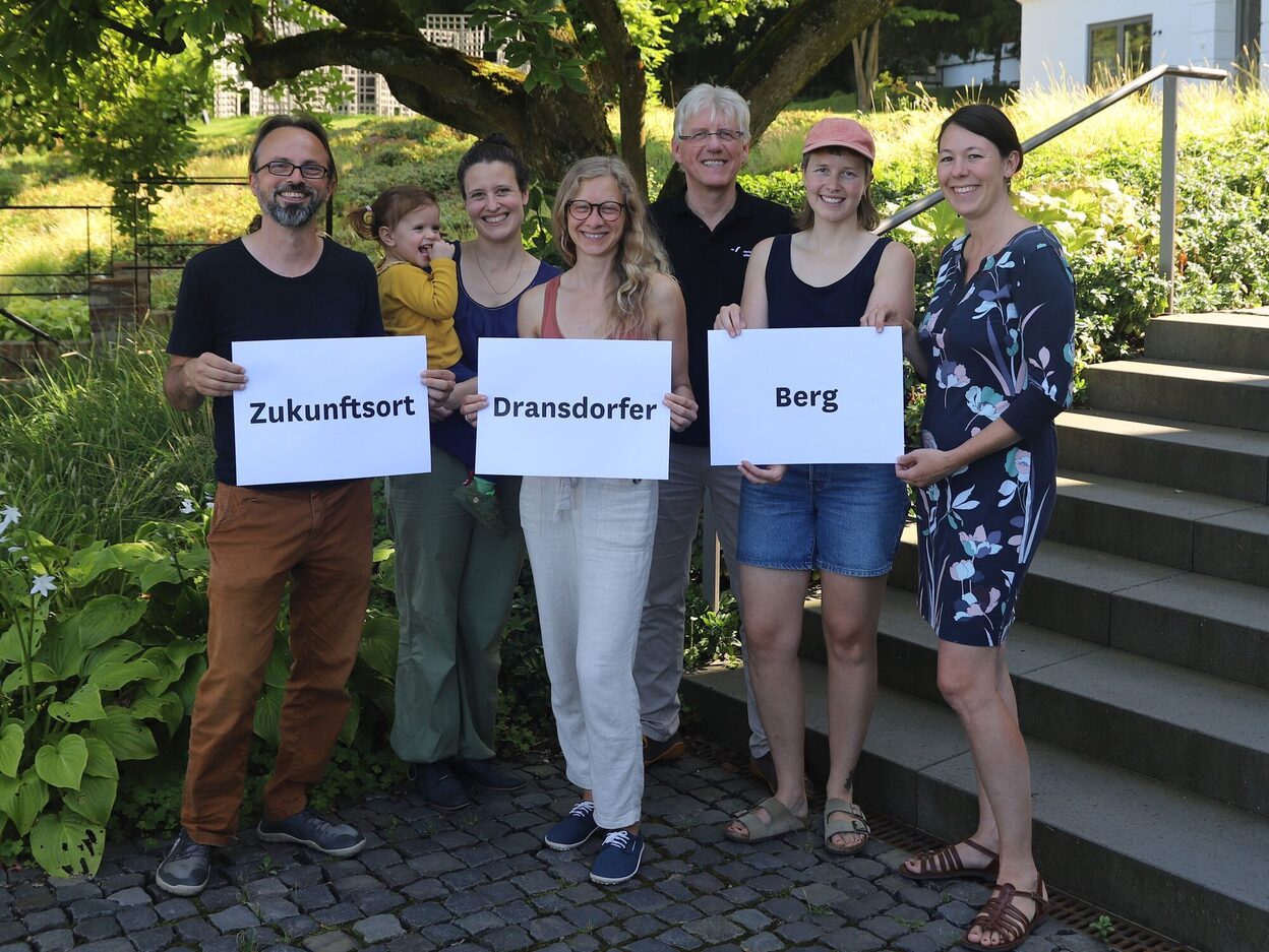 Personengruppe mit drei Schildern "Zukunftsort Dransdorfer Berg" in den Händen.