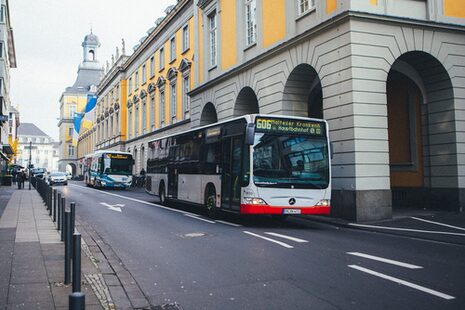 Zwei Linienbuse fährt an dem Gebäude der Uni Bonn vorbei.