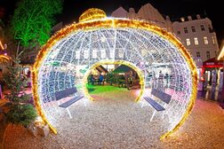 Das Foto zeigt eine große, weihnachtlich leuchtende Weihnachtskugel, die vorne und hinten geöffnet ist. Drinnen stehen zwei Sitzbänke.