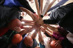 Kinder mit Basketbällen legen ihre Hände aufeinander.