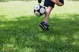 Detailaufnahme der Beine eines mit dem Fußball jonglierenden Jungen