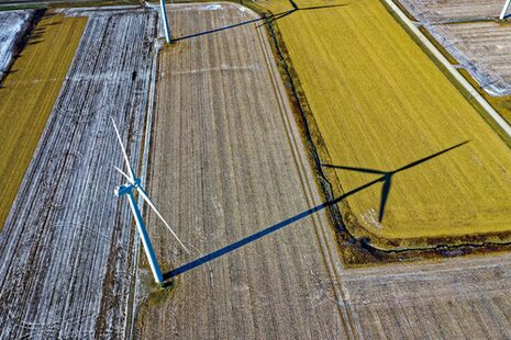 Ein Windrad auf einem Feld wirft einen langen Schatten