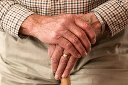Die Hände eines älteren Mannes, der sich auf einen Gehstock stützt
