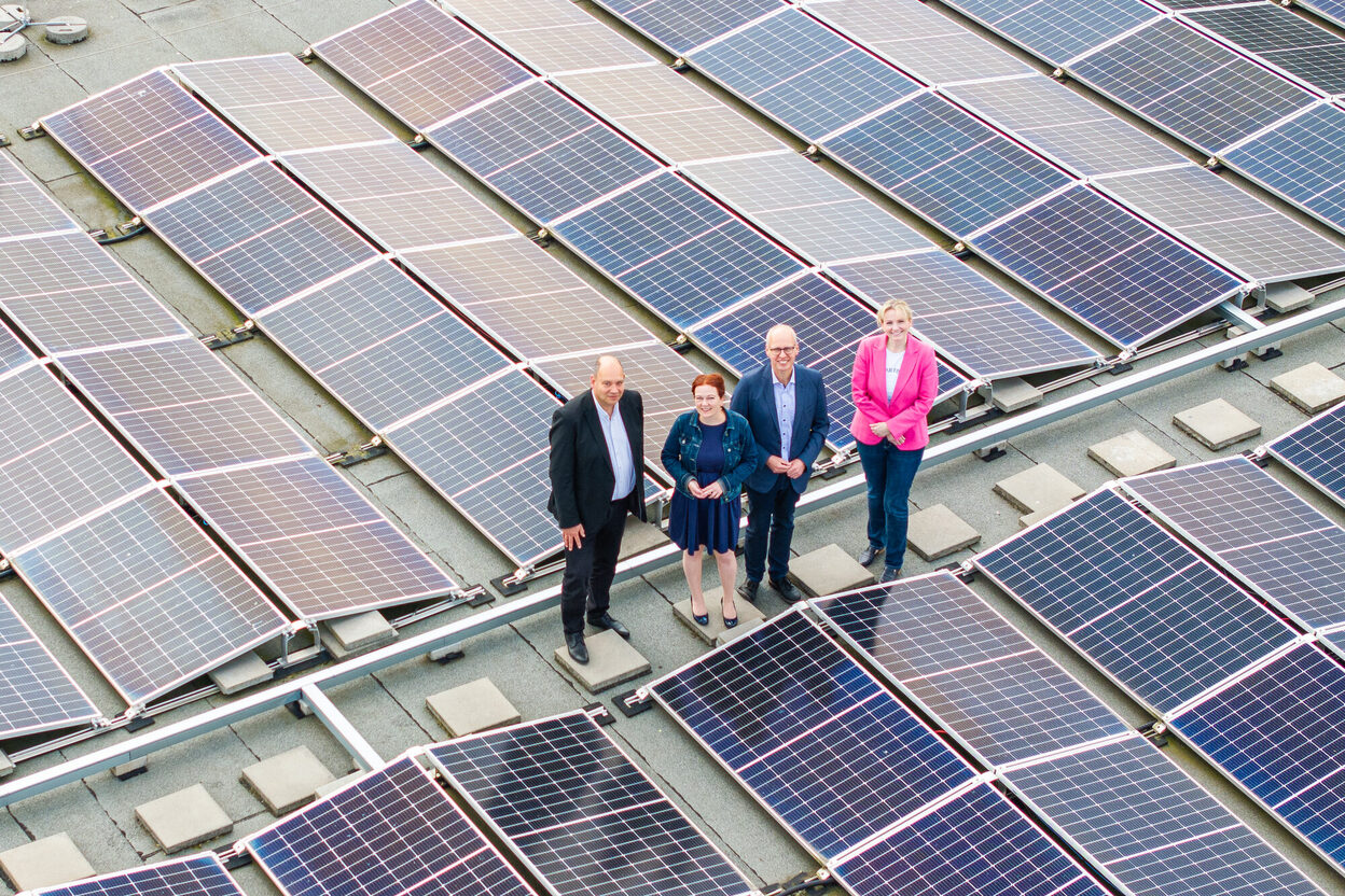 Vertreter*innen der Stadt und der Stadtwerke auf einem Flachdach mit Photovoltaikanlage.