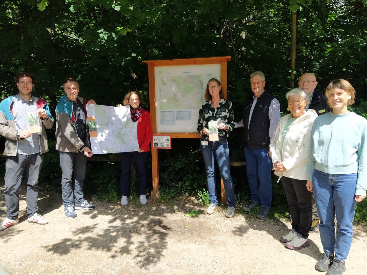 Vertreterinnen und Vertreter der Stadt Bonn, des Naturpark Rheinland und des Eifelvereins mit einer Karte an der Wandertafel an der Waldau.