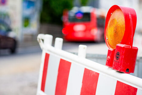 Rot-weiße Absperrung an einer Baustelle, im Hintergrund ist ein Bus zu sehen