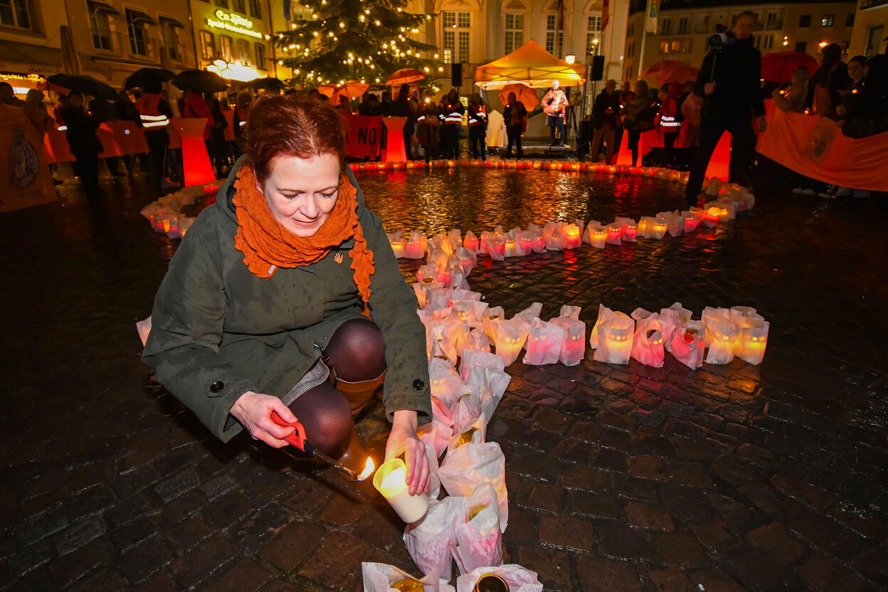 Das Bild zeigt Oberbürgermeisterin Katja Dörner, die auf dem Markt eine Kerze anzündet. Diese ist Teil eines Frauensymbols, das anlässlich des Internationalen Tages gegen Gewalt an Frauen aufgebaut wurde.