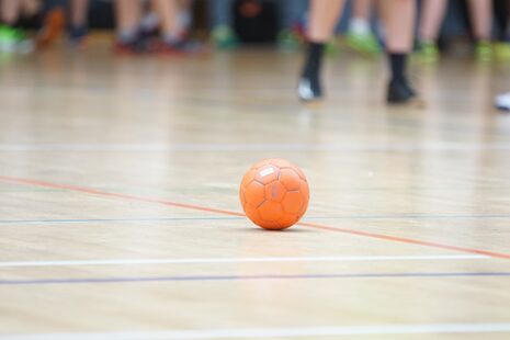 Ein oranger Handball liegt in einer Turnhalle