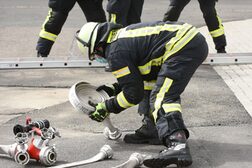 Feuerwehrleute rollen am Übungshaus Schläuche aus