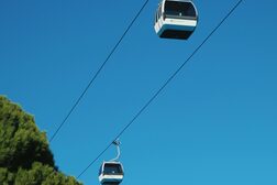 Zwei Kabinen einer Seilbahn vor blauem Himmel