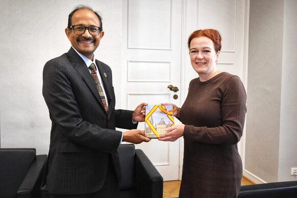 Oberbürgermeisterin Katja Dörner und UN-Generalsekretär für die Verringerung des Katastrophenrisikos, Kamal Kishore, halten ein Gastgeschenk, ein Buch über Bonn, in die Kamera.