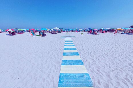 Strand mit blauem Himmel, weißem Sand und ein Fußweg