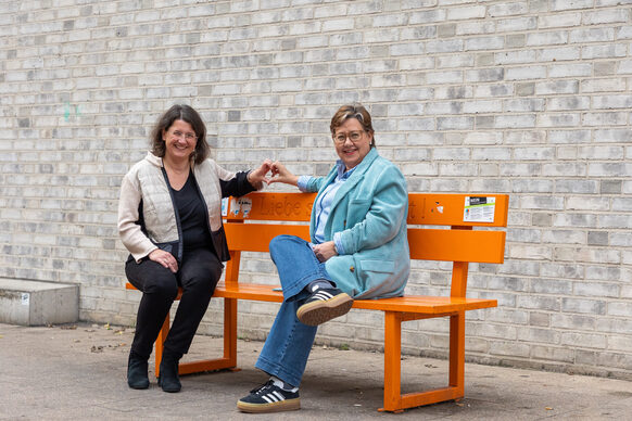 Helga Albrecht und Gabriele Tillmanns auf einer orangen Bank