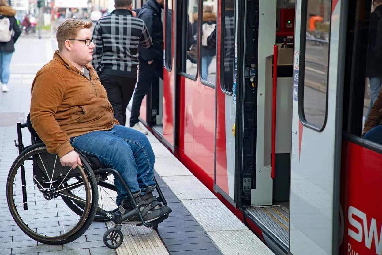 Person im Rollstuhl steigt in Stadtbahn ein