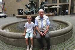 Großvater und Enkel sitzen am Martinsbrunnen in Bonn