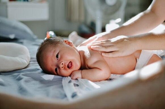 Baby liegt auf dem Bauch und wird massiert