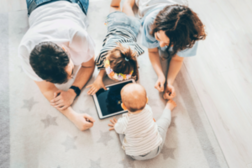 Eine Familie auf dem Boden sitzend mit einem iPad