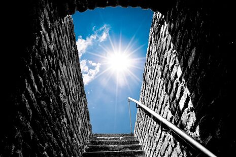 Eine Treppe aus Steinen geht aus der Burg nach draußen. Und die man sieht die Sonne.