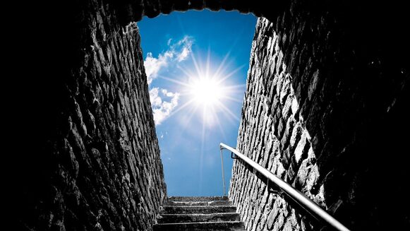 Eine Treppe aus Steinen geht aus der Burg nach draußen. Und die man sieht die Sonne.