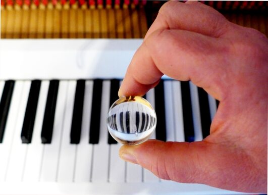 Eine Glaskugel, die über eine Klaviertastatur gehalten wird und diese spiegelverkehrt anzeigt.