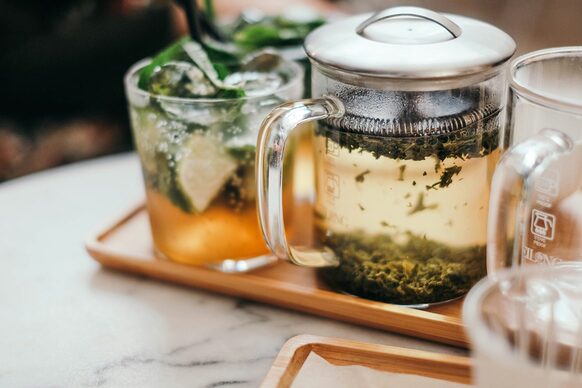 Teeglas und Teekanne aus Glas auf einem Holztablett