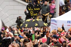Verkleidete Menschenmenge und ein Regenschirm mit Herz auf der Spitze mit Aufschrift "Wir sind Prinz".