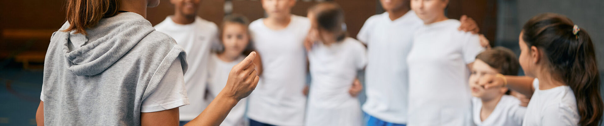 Jugendliche mit einer Lehrperson in einer Turnhalle